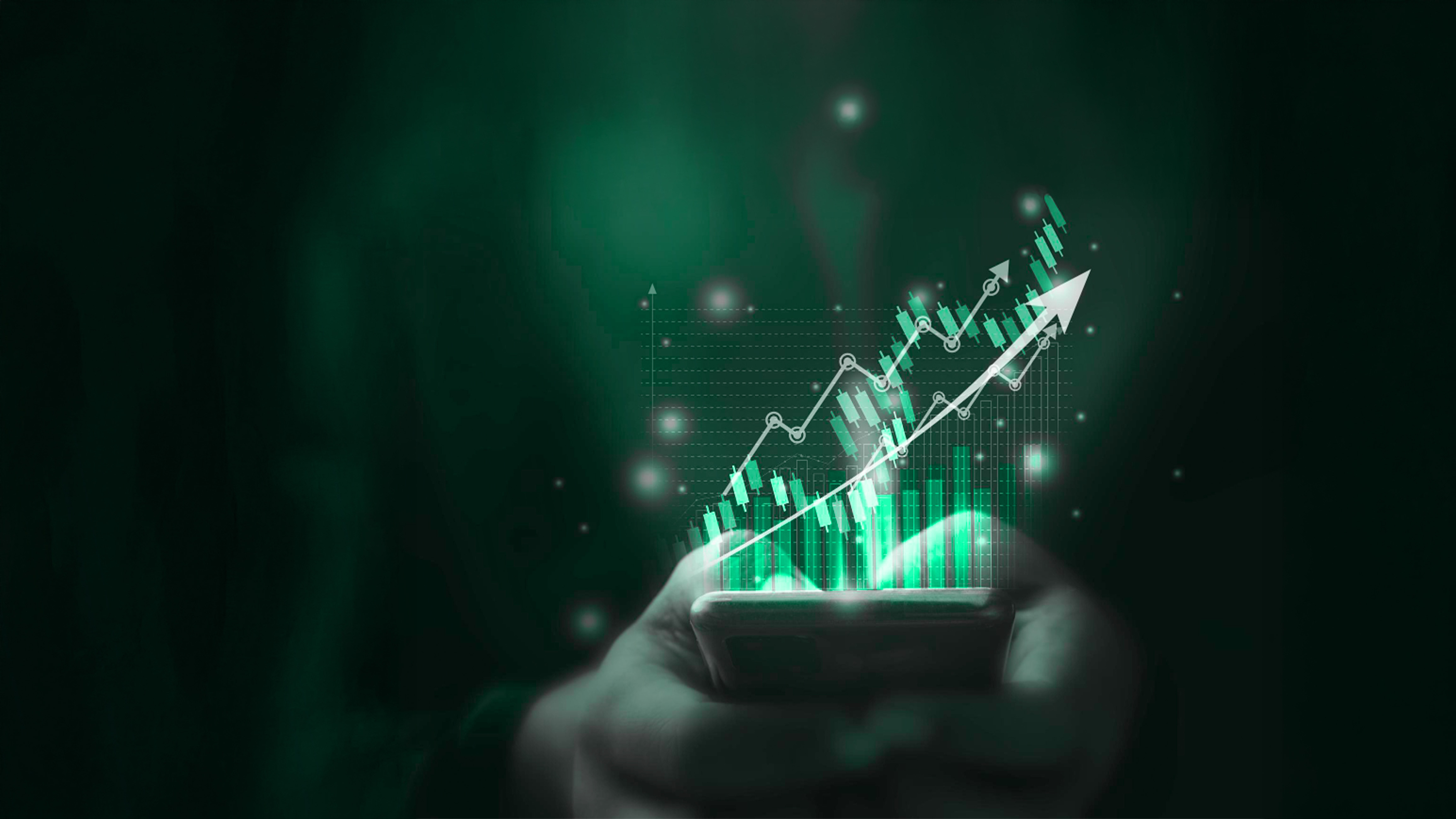 Trader monitoring charts on laptop and phone